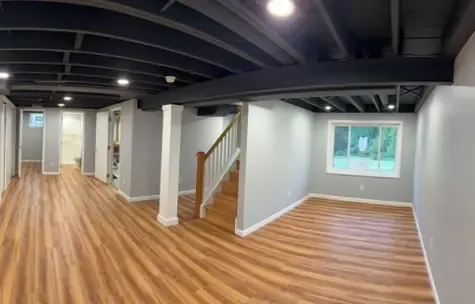 Finished basement with luxury vinyl plank flooring and recessed lighting.