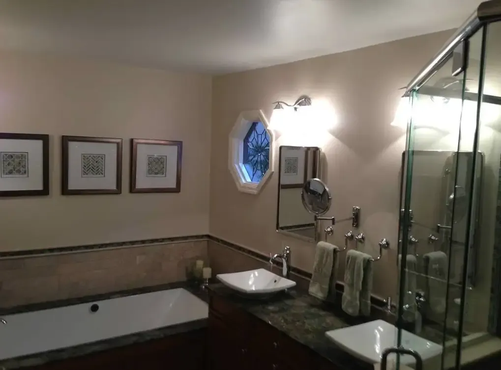 Remodeled bathroom with tiled tub surround, stone vanity and glass shower.